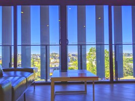 Una habitación con amplios ventanales, una mesa de madera y un sofá de cuero.