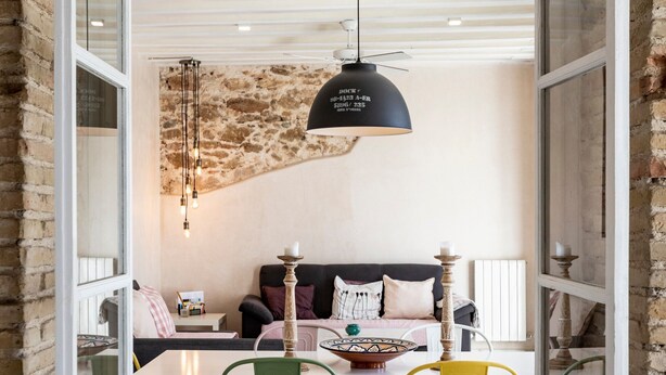 An open-plan living and dining area with a brick wall, a sofa set, a dining table with chairs, and pendant lighting. - Rustic Apartment "Casa Bugambilla" in Very Central Location with Balcony & Wi-Fi (Cadiz)