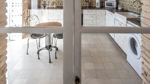 A kitchen with wooden beams, a dining area with a table and chairs, and a washing machine. - Rustic Apartment "Casa Bugambilla" in Very Central Location with Balcony & Wi-Fi (Cadiz)