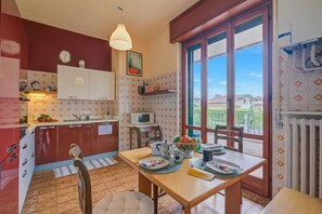 A kitchen with a dining area, a microwave, a clock, and a view of the outside.
