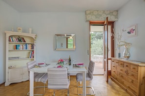 A dining area with a white table, striped chairs, a wooden cabinet, and a bookshelf. - Connie's apartment Extra Pet Friendly (Monvalle)