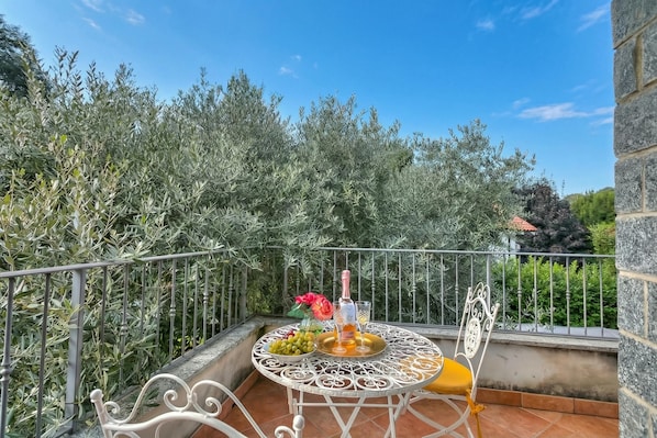 A balcony with a round table, a chair, and a railing.