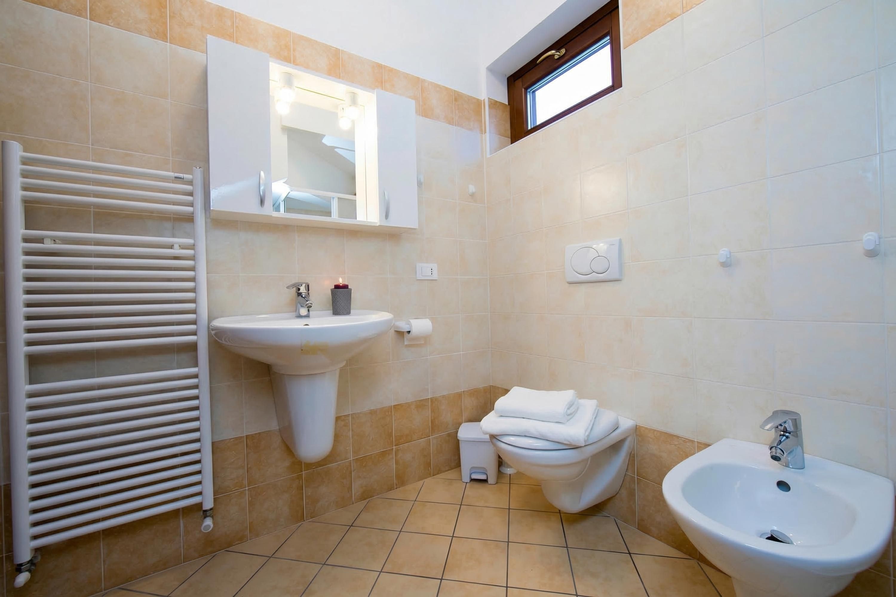 Een badkamer met een wit wastafel, een toilet, een bidet en een radiator.