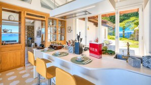 A modern kitchen with a large island, wooden cabinets, and a view of the outdoors. - Paradis Relais Infinity Pool Lake View (Belgirate)