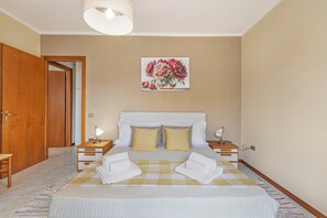 Une chambre d’hôtel avec un lit, des tables de chevet, une commode, une lampe et un tableau au mur.