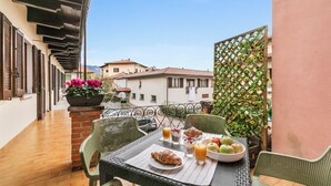 A balcony with a table set for breakfast, including croissants, fruit, and juice. - Petalo Bianco 100m from lake (Baveno)