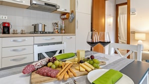 A kitchen with a dining table set for a meal, featuring cheese, grapes, and cured meats. - Petalo Bianco 100m from lake (Baveno)