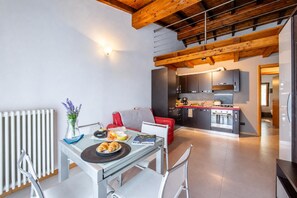 A modern kitchen with a built-in oven and a dining area with a table and chairs. - Relax al Moro Apt with Pool (Leggiuno)