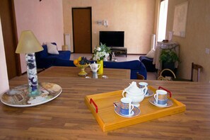 A living room with a wooden floor, a sofa, a TV, a coffee table with a tray of tea cups, and a lamp. - Sunflower Relax Pool and Terrace (Lesa)