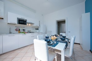 A modern kitchen with white cabinetry, a microwave, and a dining area with a table set for four.