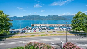 Uma marina com barcos atracados, uma estrada em primeiro plano e montanhas ao fundo.