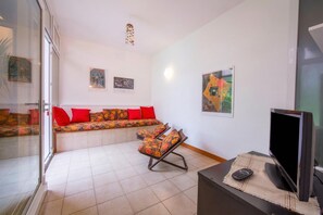 A living room with a sofa, a chair, a TV, and artwork on the wall. - Rododendro Rosso (Ispra)
