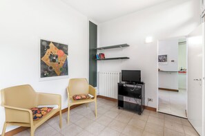 A room with two wicker chairs, a black entertainment unit, and a painting on the wall.