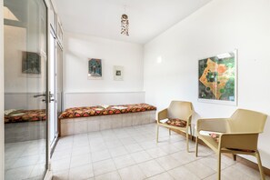 Una habitación con un banco, dos sillas, un ventanal de vidrio y obras de arte en las paredes.