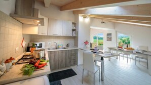 Une cuisine moderne équipée d’une cuisinière, d’un four à micro-ondes et de meubles de rangement en bois.