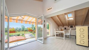 Une pièce spacieuse dotée d’une grande porte-fenêtre coulissante donnant sur un patio extérieur, d’un coin repas avec une table et des chaises, et d’un espace cuisine avec un comptoir et des placards.