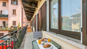 A balcony with a table set for breakfast, including croissants, yogurt, and orange juice.