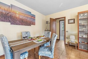 A dining area with a wooden table, chairs, and a painting of a sunset. - Sunrise in Baveno (Baveno)
