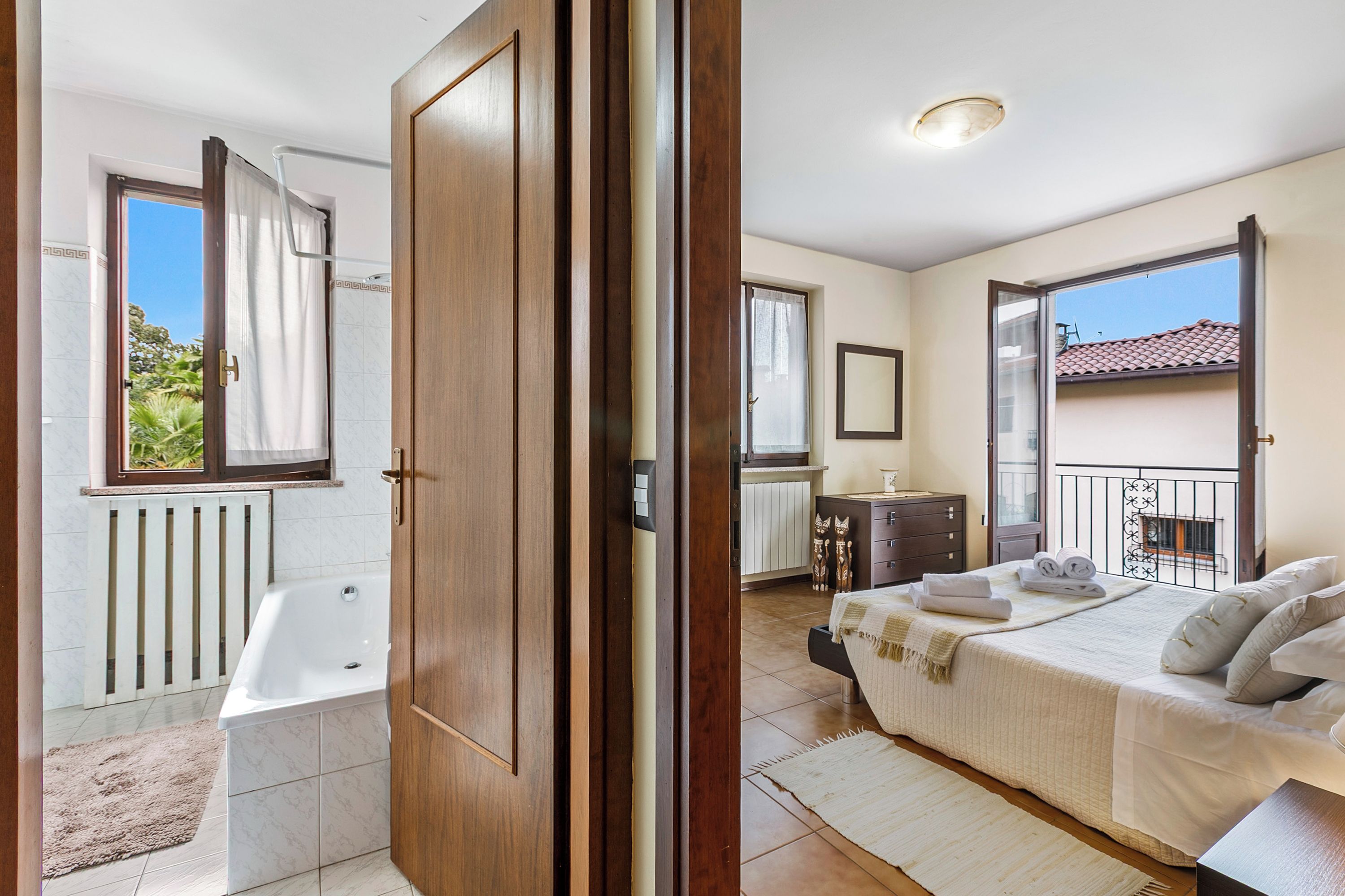 A bedroom with a large bed, a bedside table, a window, and a view of the outside.