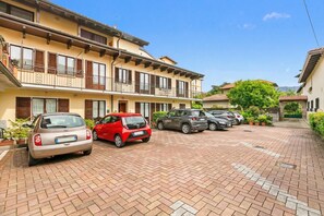 A residential building with a parking area, multiple cars, and a clear sky. - Sunset in Baveno (Baveno)