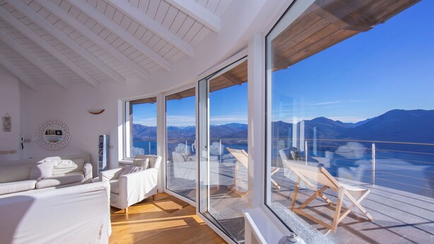 Een moderne kamer met een grote schuifglazen deur naar een balkon met uitzicht op de bergen.