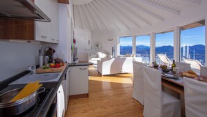 Een moderne keuken met houten vloeren, een eethoek met uitzicht en een witte eethoekset.