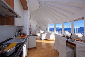 Una cocina moderna con suelo de madera, un comedor con vistas y un juego de comedor blanco.