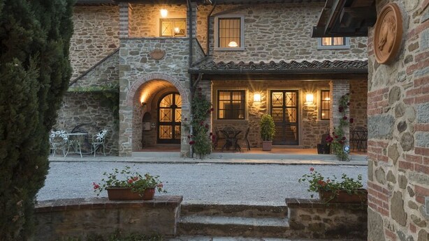 A stone building with a patio, outdoor seating, and a staircase leading to an upper level. - Agriturismo Incrociata (Bucine)