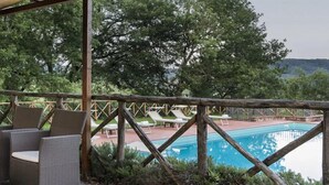 A covered outdoor area with a pool, lounge chairs, and a wooden deck. - Agriturismo Incrociata (Bucine)
