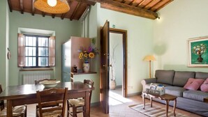 A cozy living room with a dining area, a sofa, a lamp, and a painting on the wall. - Agriturismo Incrociata (Bucine)