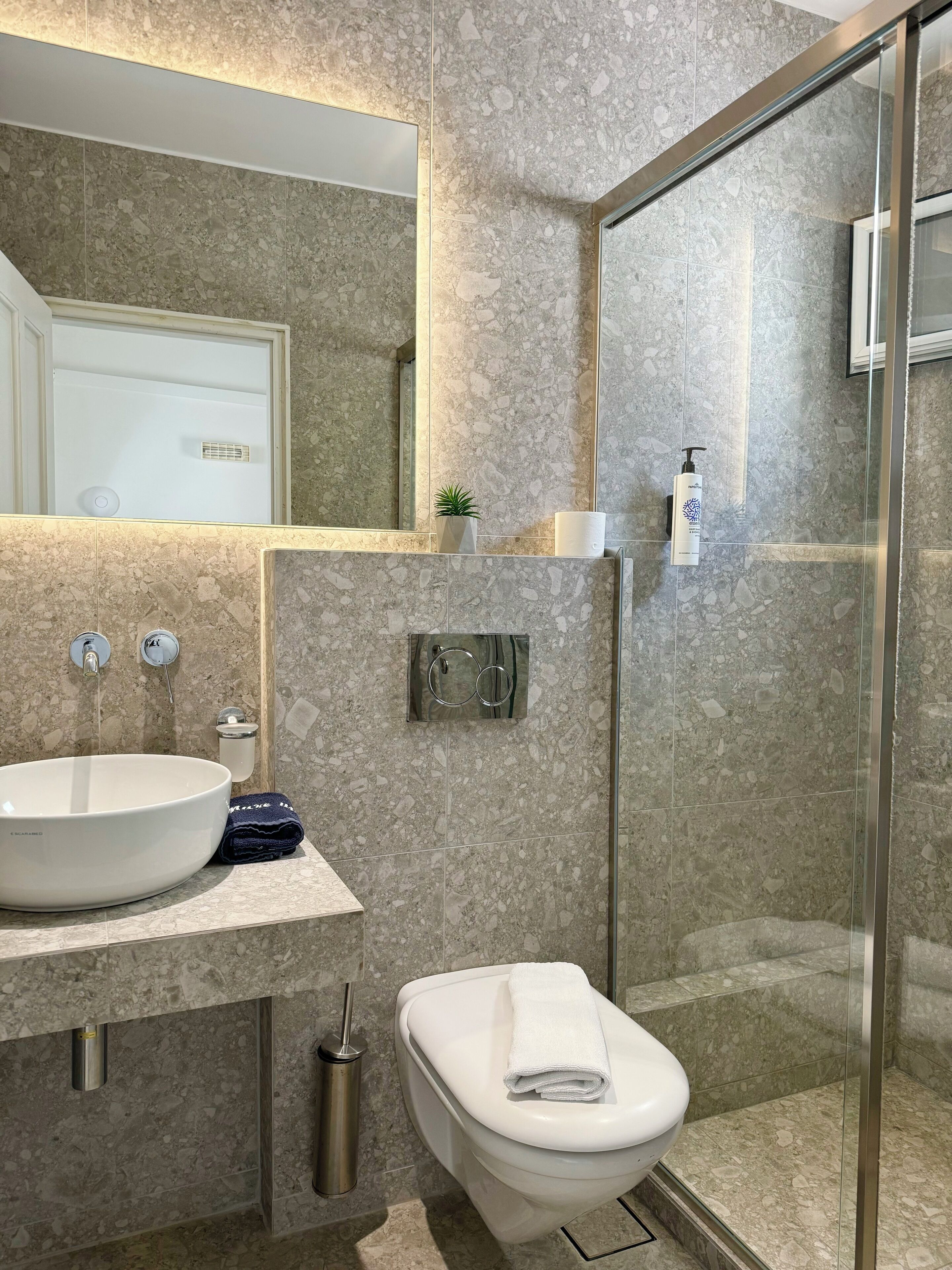 Un baño moderno con un lavamanos grande, inodoro y cabina de ducha de vidrio.