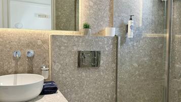 Un baño moderno con un lavamanos grande, inodoro y cabina de ducha de vidrio.