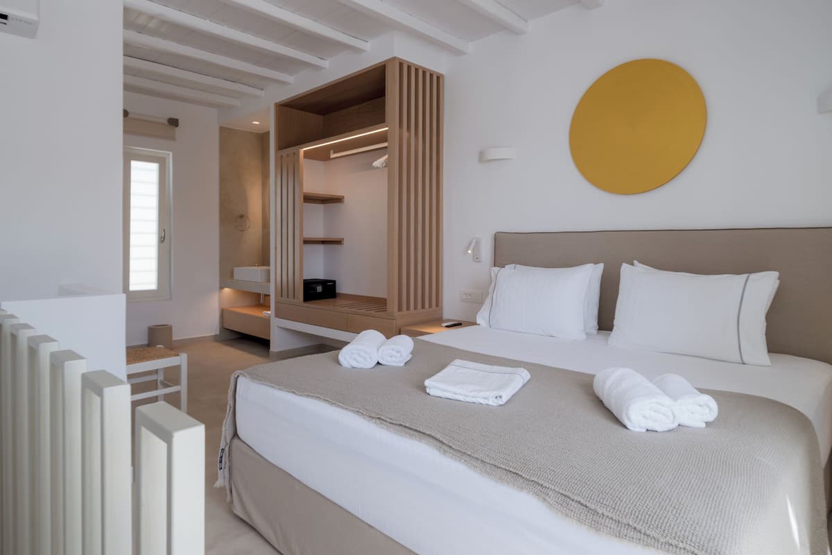 A modern hotel room with a large bed, a walk-in closet, and a circular wall decoration.