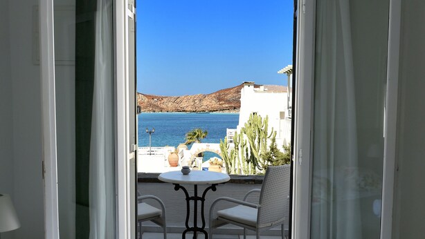 A room with a bed, a table, and a view of the sea. - Anthos Apartments Paros (Paros)