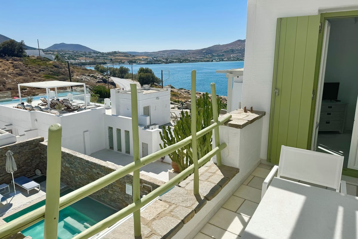 A modern building with a pool, a view of the sea, and a green door.
