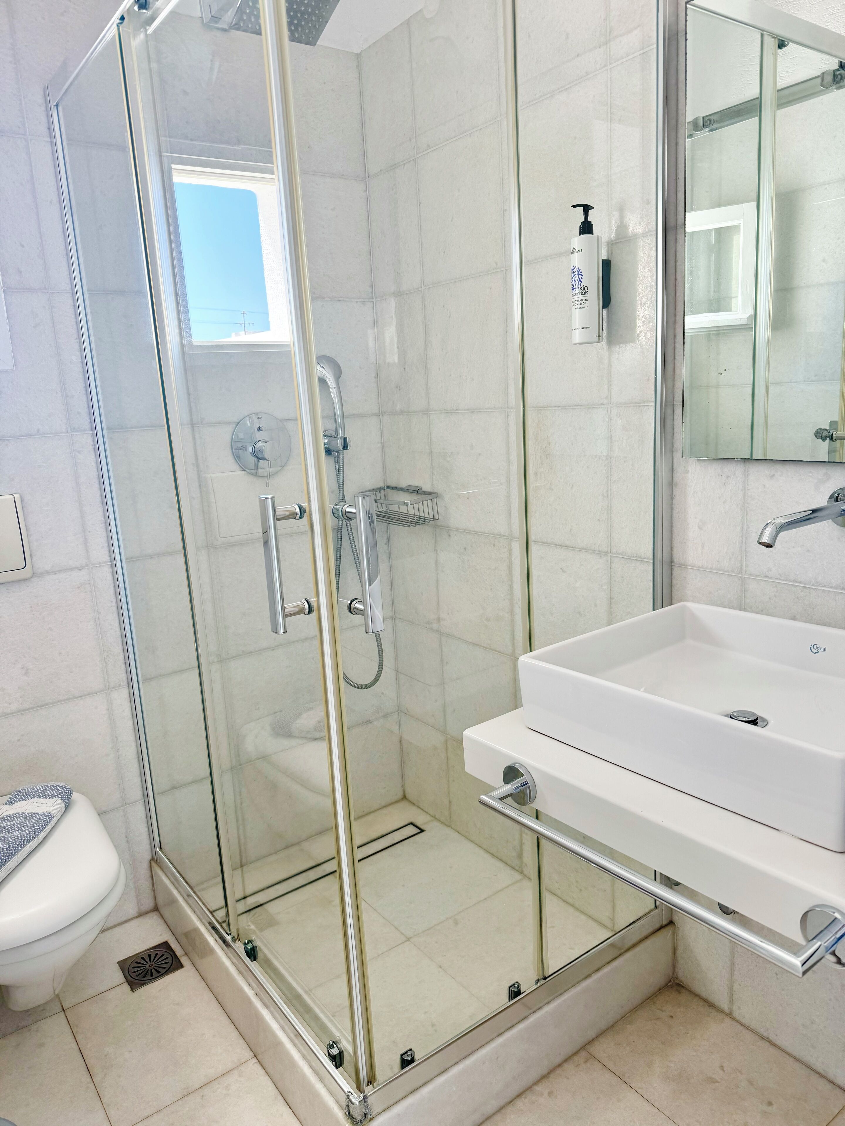 A modern bathroom with a glass-enclosed shower, a white sink, and a toilet.