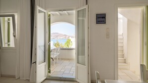 An open door leading to a balcony with a view of the sea and hills. - Anthos Apartments Paros (Paros)