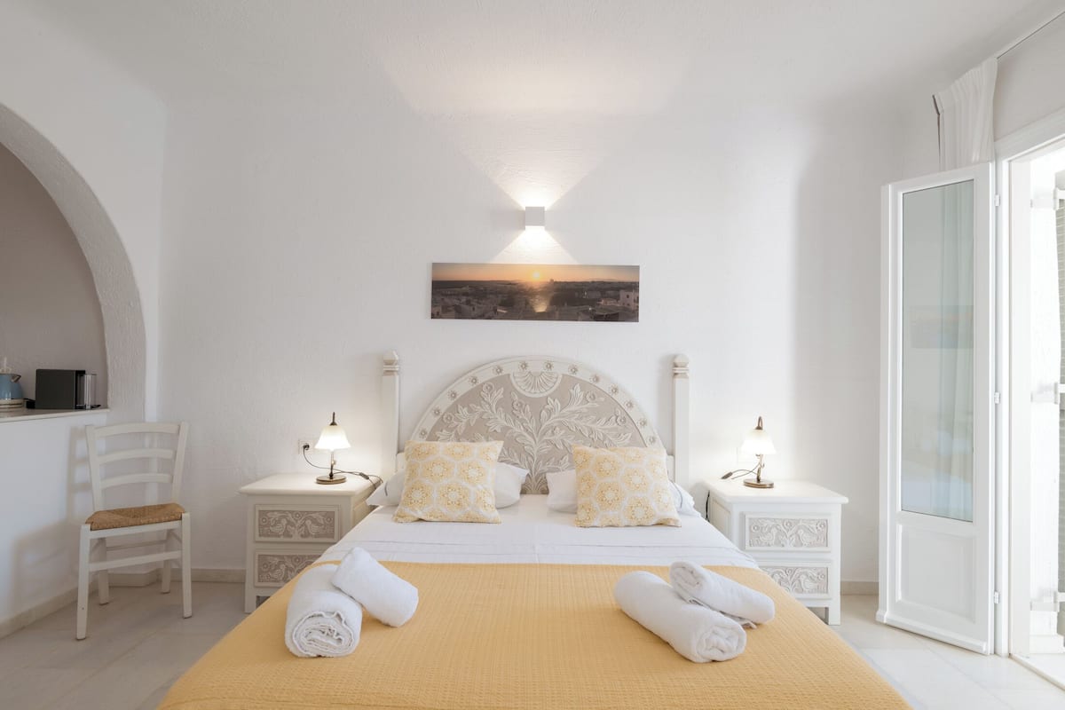 A hotel room with a bed, two bedside tables, a chair, a window, and a wall-mounted picture.