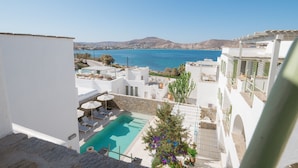 A rooftop pool area with clear blue sea views, white architecture, and a stone wall. - Anthos Apartments Paros (Paros)