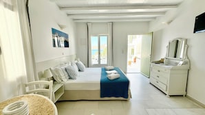 A bedroom with a bed, a dresser, a chair, and a table. - Anthos Apartments Paros (Paros)