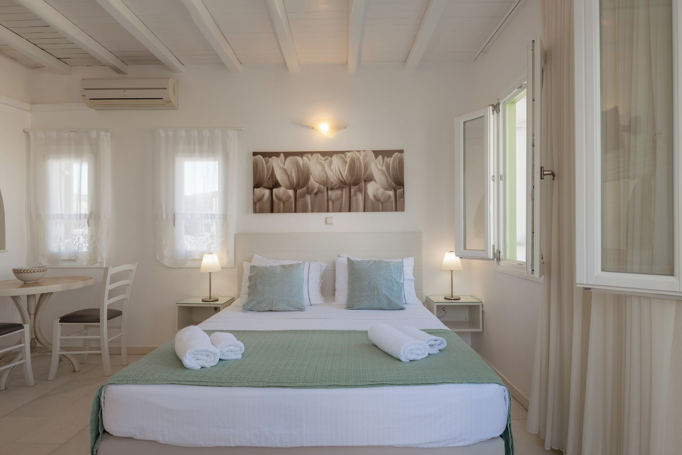 Habitación de hotel ordenada con cama, mesitas de noche, un escritorio pequeño y una silla.