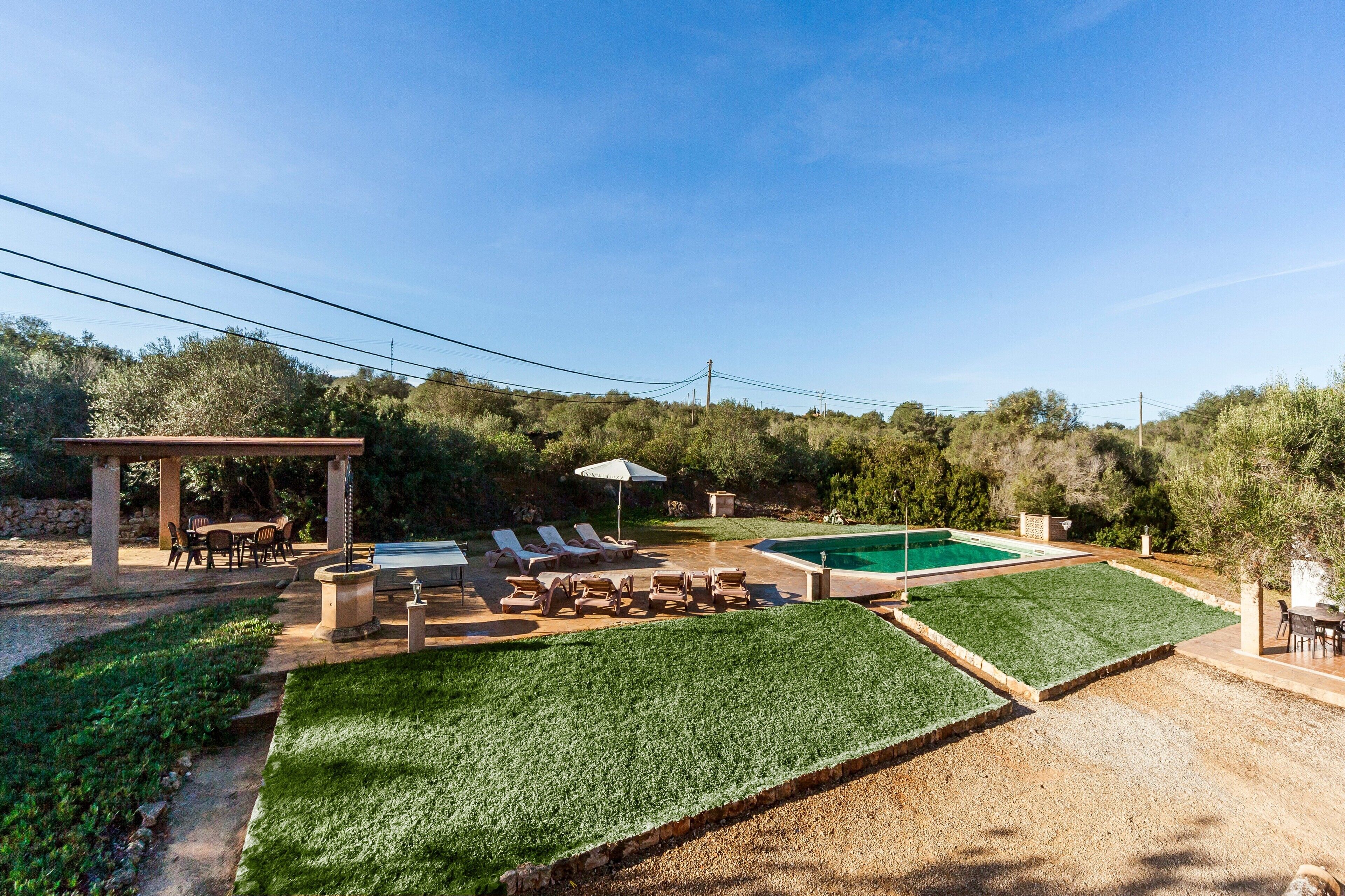 Un jardin avec une piscine, des chaises longues, une pergola et un espace repas.