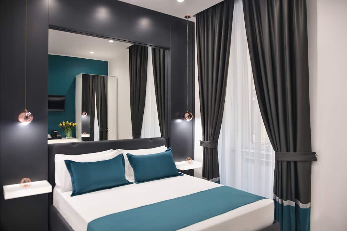 A modern bedroom with a large bed, dark walls, and a large mirror.