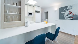 A modern kitchen with white cabinetry, a microwave, and a toaster. There are two blue chairs at the counter. - Beautiful Apartment "Venecia" with Pool, Wi-Fi, Balcony & A/C (Alcudia)