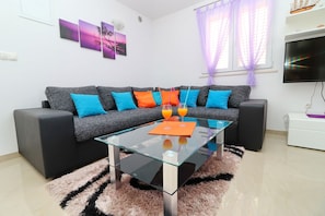 A modern living room with a sectional sofa, a glass coffee table, and a fluffy rug.