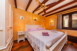 A bedroom with a bed, bedside tables, a ceiling fan, and a window with curtains.