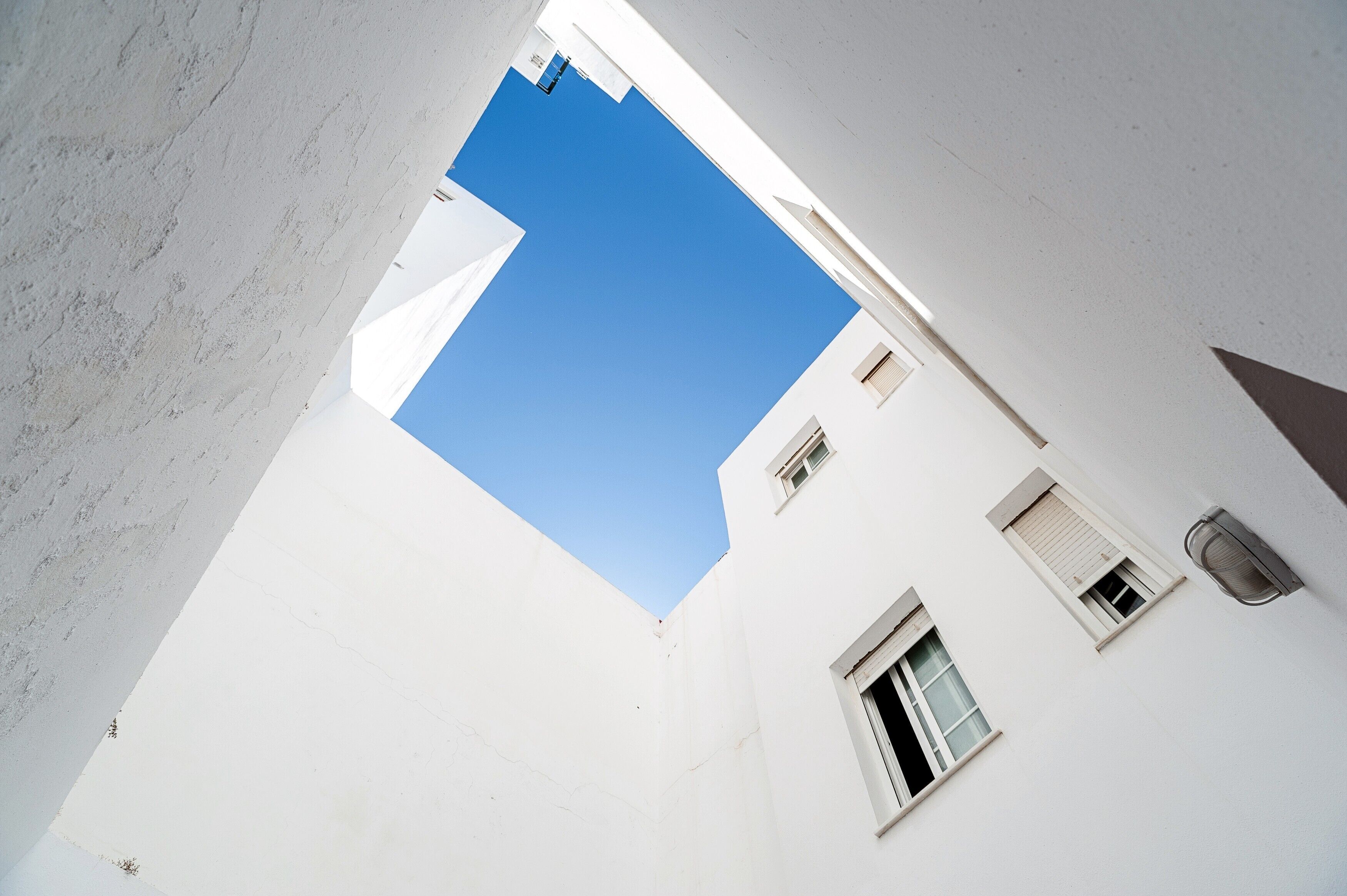 Un bâtiment blanc, avec un ciel bleu clair visible à travers une étroite ouverture.