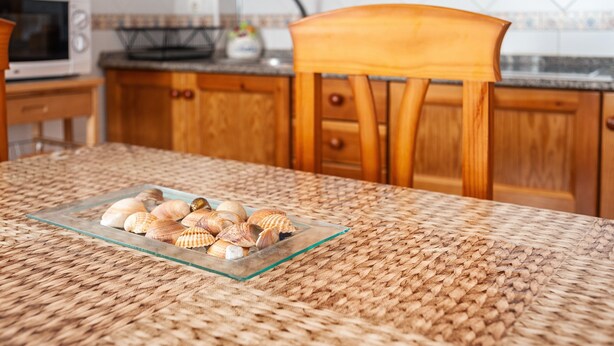 A kitchen with wooden cabinets, a microwave, and a woven tablecloth. - Charming Apartment in Great Location Near the Beach with Terrace; Pets Allowed under request (Conil de la Frontera)