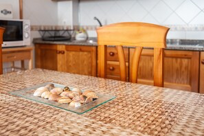 A kitchen with wooden cabinets, a microwave, and a woven tablecloth. - Charming Apartment in Great Location Near the Beach with Terrace; Pets Allowed under request (Conil de la Frontera)