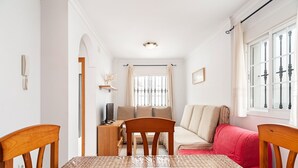A dining area with a table, chairs, a TV, and a sofa. - Charming Apartment in Great Location Near the Beach with Terrace; Pets Allowed under request (Conil de la Frontera)